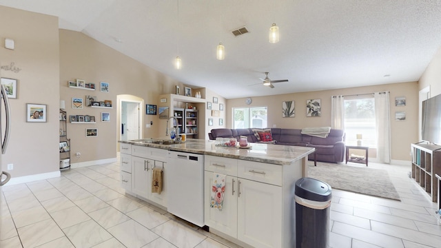 kitchen featuring a center island, vaulted ceiling, dishwasher, light stone countertops, and white cabinets