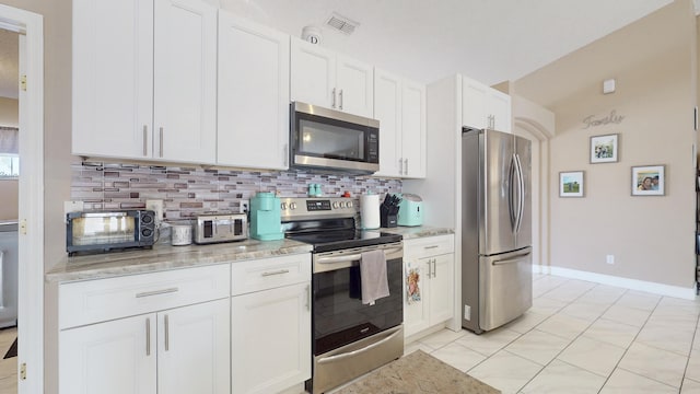 kitchen with tasteful backsplash, white cabinetry, appliances with stainless steel finishes, and light stone counters