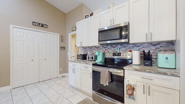 kitchen featuring tasteful backsplash, appliances with stainless steel finishes, white cabinets, and light stone counters