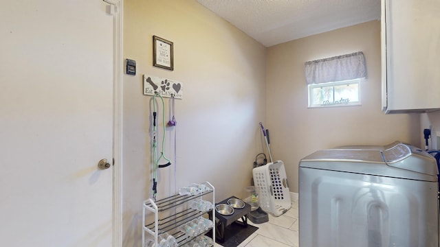 washroom with cabinets, independent washer and dryer, a textured ceiling, and light tile patterned floors