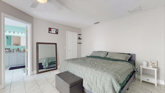 bedroom with connected bathroom, a textured ceiling, light tile patterned floors, and ceiling fan