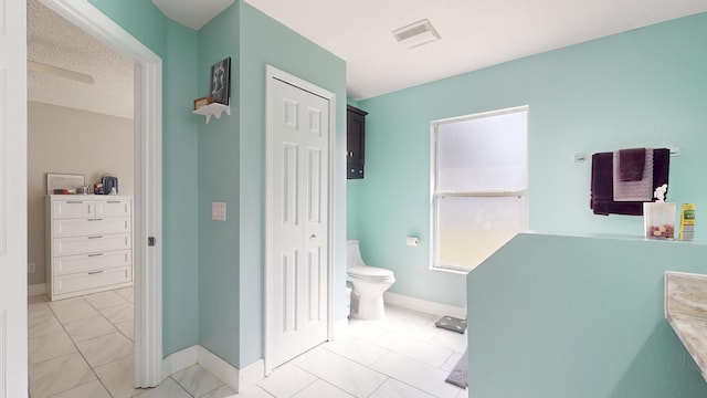 bathroom with tile patterned floors, toilet, and a textured ceiling