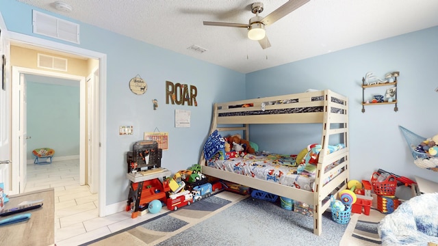 tiled bedroom featuring ceiling fan and a textured ceiling