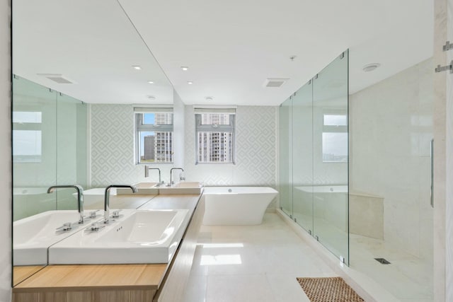bathroom with double vanity, a freestanding bath, a shower stall, tile walls, and tile patterned floors