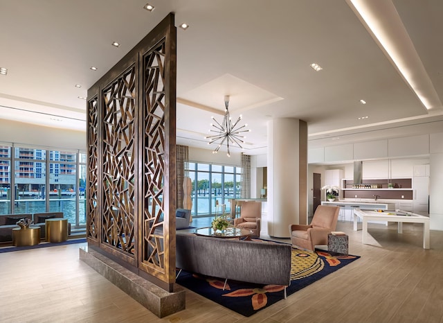 living room featuring a chandelier, a raised ceiling, and light wood-style flooring