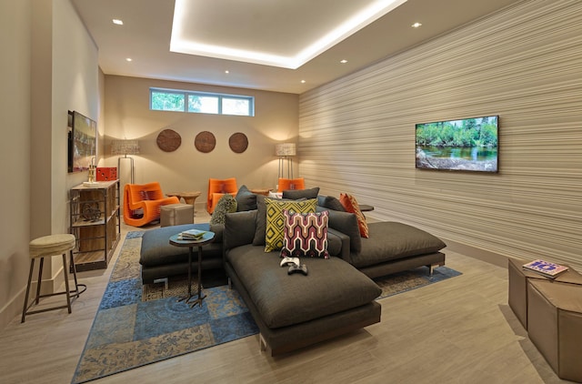 living area with recessed lighting, a raised ceiling, wood finished floors, and an accent wall