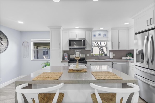 kitchen featuring sink, appliances with stainless steel finishes, white cabinetry, light stone countertops, and decorative backsplash