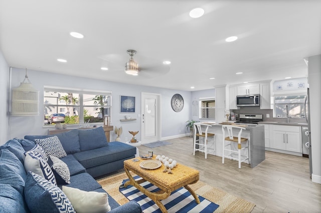 living room with light wood finished floors, baseboards, and recessed lighting