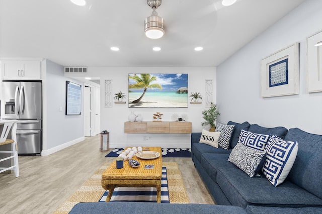 living room with baseboards, light wood-type flooring, visible vents, and recessed lighting