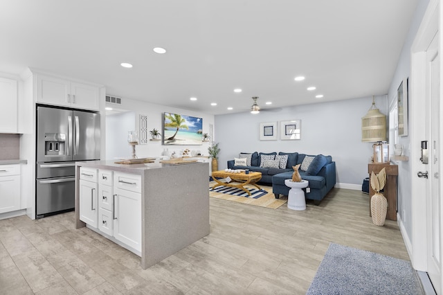 kitchen with a kitchen island, white cabinetry, visible vents, open floor plan, and stainless steel fridge with ice dispenser