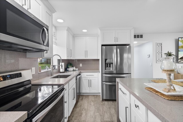 kitchen with white cabinetry, light hardwood / wood-style flooring, and a center island with sink