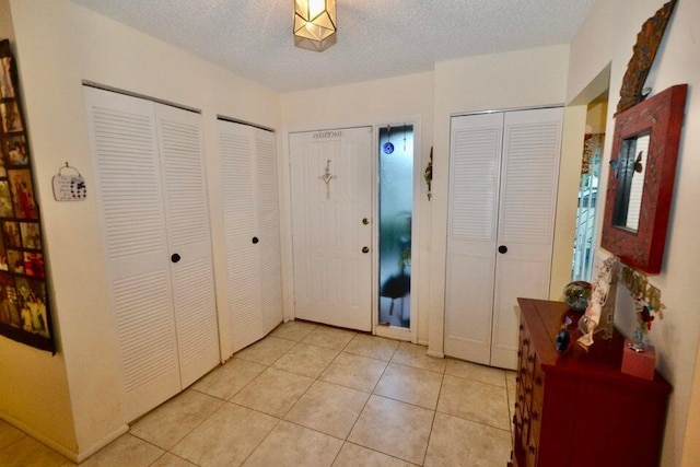 foyer entrance with light tile patterned flooring and a textured ceiling