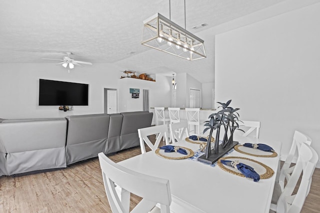 dining area with lofted ceiling, ceiling fan, wood-type flooring, and a textured ceiling