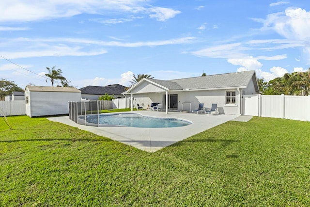 rear view of house featuring a fenced in pool, a patio, a storage unit, and a lawn