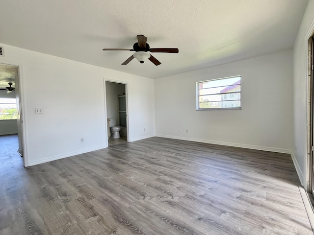 empty room featuring ceiling fan, light wood-type flooring, a textured ceiling, and a wealth of natural light