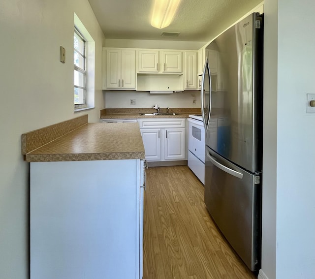 kitchen featuring electric stove, sink, white cabinets, stainless steel fridge, and light hardwood / wood-style flooring