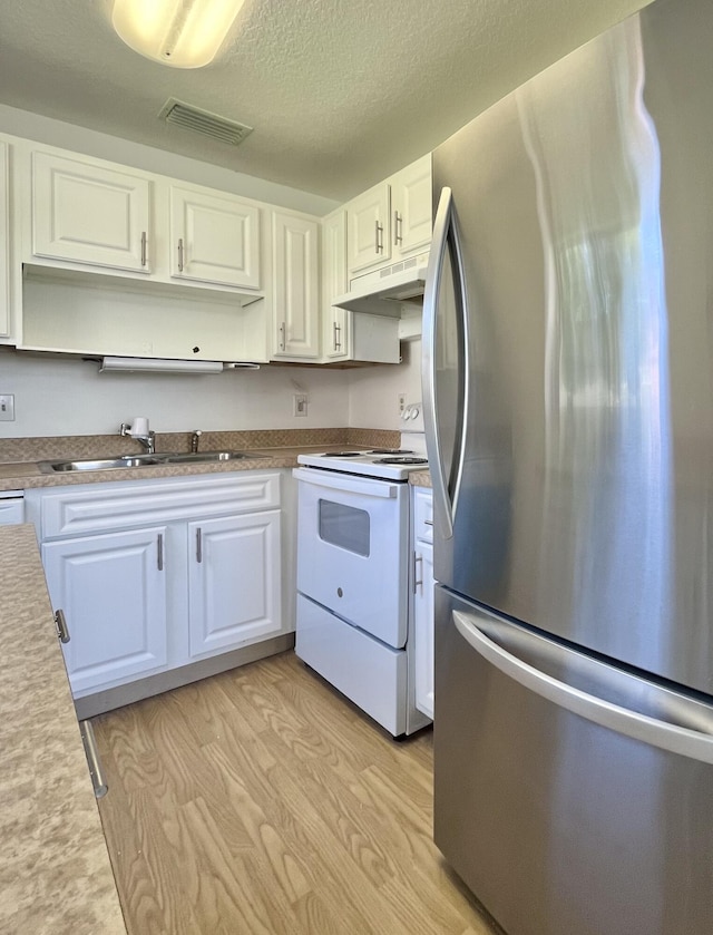 kitchen with stainless steel refrigerator, white cabinetry, light hardwood / wood-style floors, a textured ceiling, and electric stove