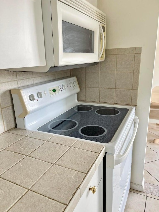 kitchen with white cabinetry, backsplash, and white appliances