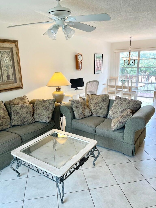 tiled living room featuring ceiling fan with notable chandelier and a textured ceiling