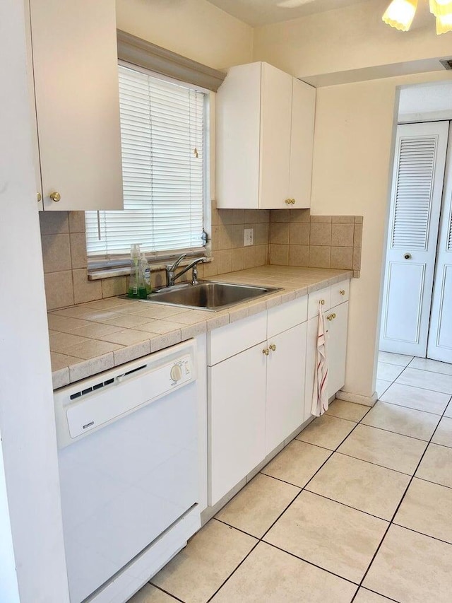 kitchen featuring white dishwasher, sink, white cabinetry, and decorative backsplash