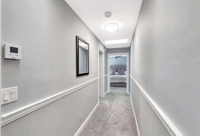 corridor featuring light carpet and a skylight