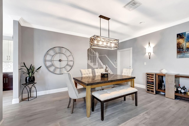 dining room featuring crown molding, beverage cooler, and light hardwood / wood-style floors