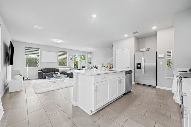 kitchen featuring stainless steel appliances, sink, an island with sink, and white cabinets