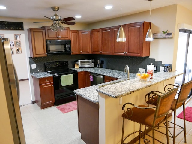 kitchen featuring light stone countertops, pendant lighting, kitchen peninsula, and black appliances