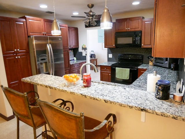 kitchen featuring tasteful backsplash, kitchen peninsula, a kitchen bar, and black appliances