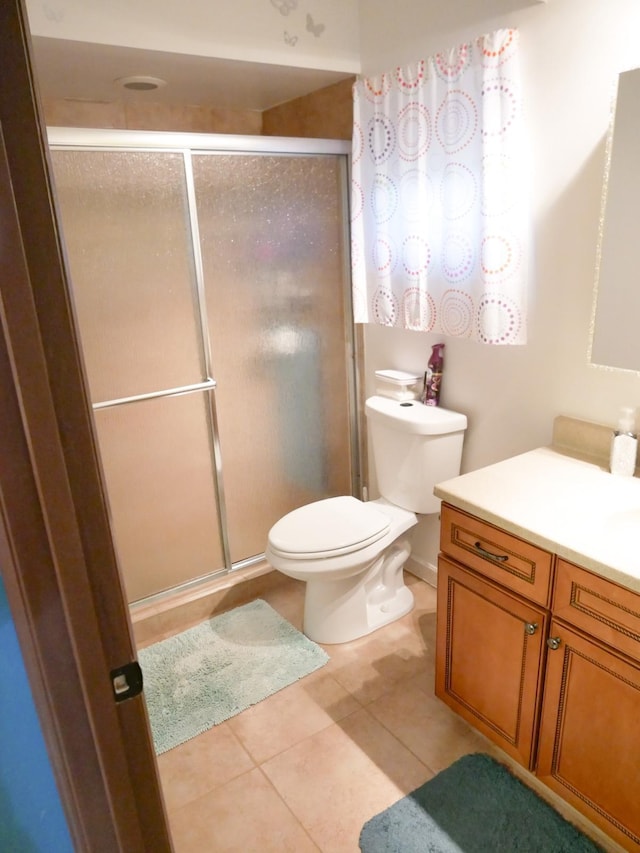 bathroom with tile patterned flooring, vanity, a shower with door, and toilet