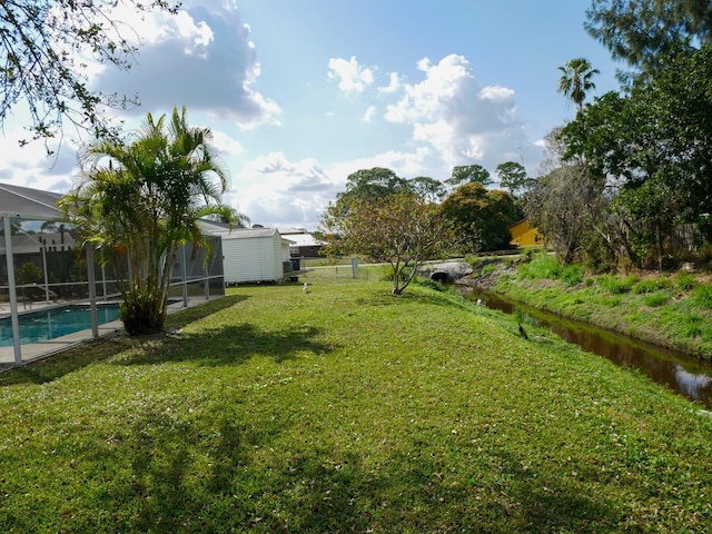 view of yard with a water view and glass enclosure