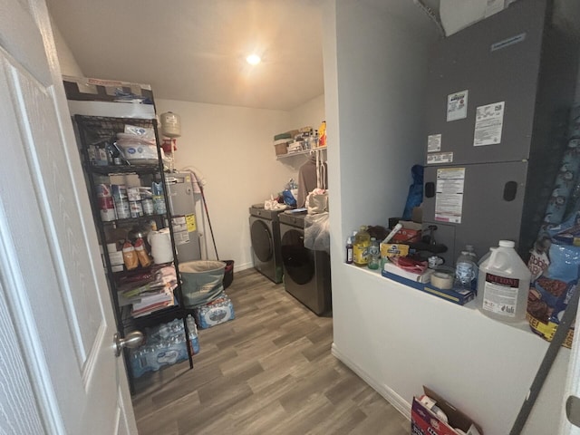 laundry room featuring water heater, hardwood / wood-style flooring, and washer and dryer