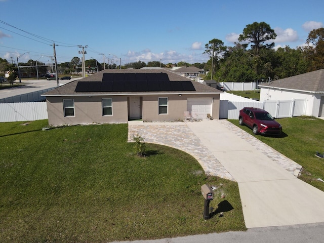 view of front of home with a garage, a front yard, and solar panels