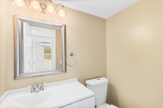 bathroom featuring vanity, a chandelier, an AC wall unit, and toilet