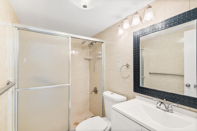 bathroom with tile walls, an enclosed shower, vanity, and toilet