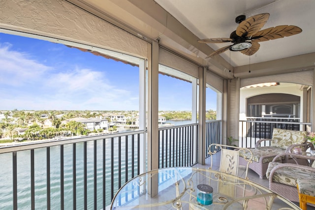 sunroom / solarium featuring a water view and ceiling fan