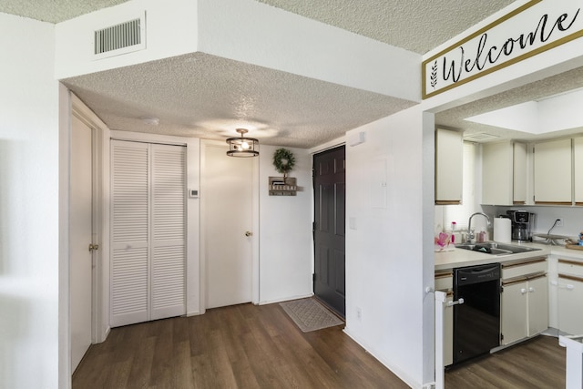 kitchen with dishwasher, sink, white cabinets, dark wood-type flooring, and a textured ceiling