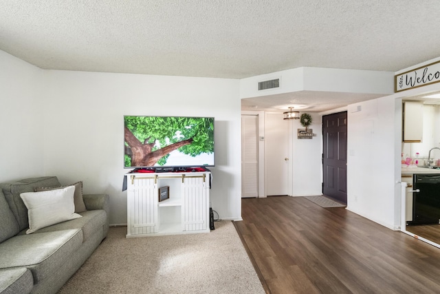 living room featuring hardwood / wood-style flooring, sink, and a textured ceiling