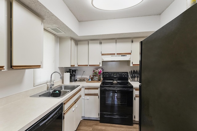 kitchen featuring wood-type flooring, sink, white cabinets, and black appliances