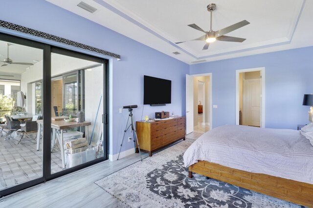 bedroom featuring wood-type flooring, access to exterior, ceiling fan, and a tray ceiling