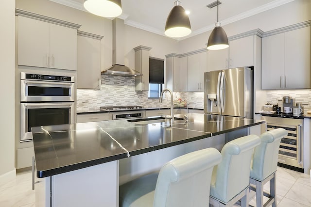 kitchen featuring sink, a center island with sink, appliances with stainless steel finishes, pendant lighting, and beverage cooler