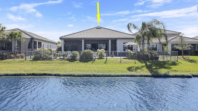 back of property with a water view, a sunroom, and a lawn