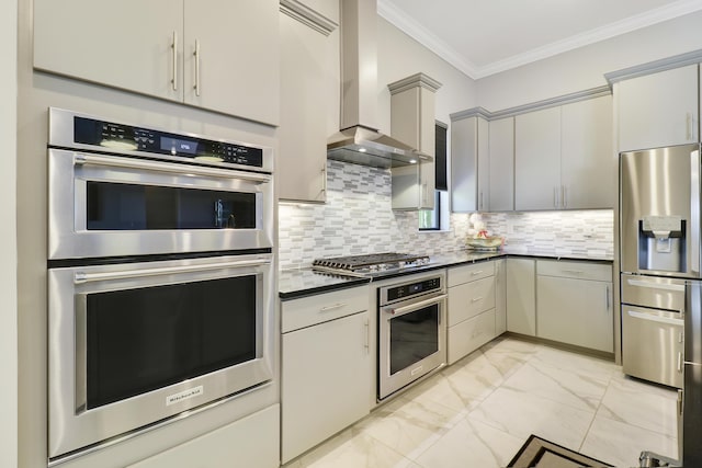 kitchen featuring crown molding, gray cabinets, stainless steel appliances, decorative backsplash, and wall chimney range hood