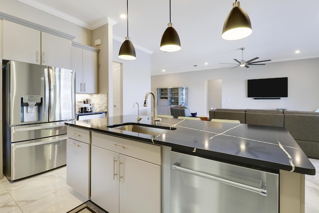 kitchen with sink, crown molding, appliances with stainless steel finishes, tasteful backsplash, and an island with sink