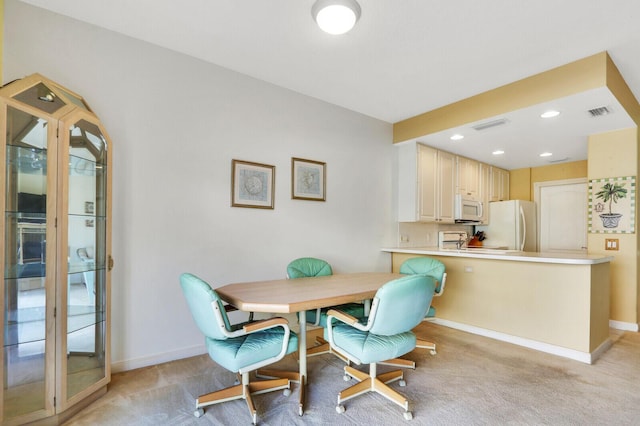 dining space featuring light carpet