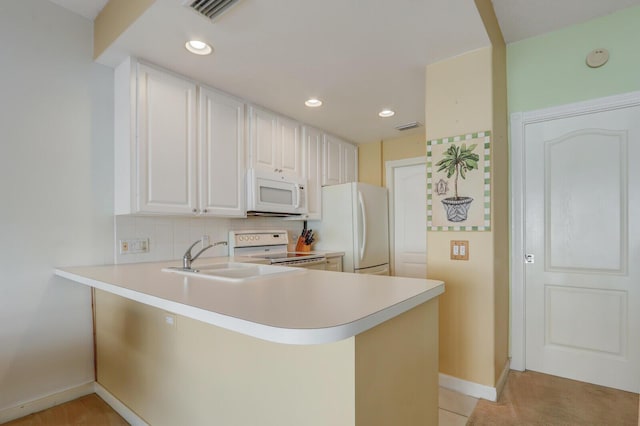 kitchen featuring sink, white appliances, kitchen peninsula, and white cabinets