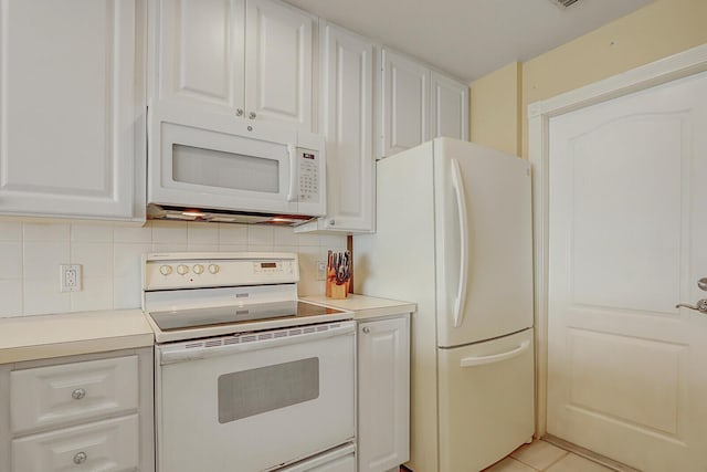 kitchen featuring tasteful backsplash, white appliances, light tile patterned floors, and white cabinets