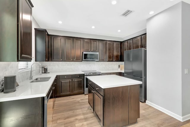 kitchen featuring appliances with stainless steel finishes, sink, a center island, dark brown cabinetry, and light hardwood / wood-style floors