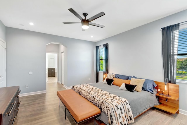 bedroom with connected bathroom, wood-type flooring, and ceiling fan