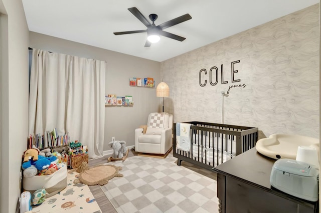 bedroom with a nursery area and ceiling fan